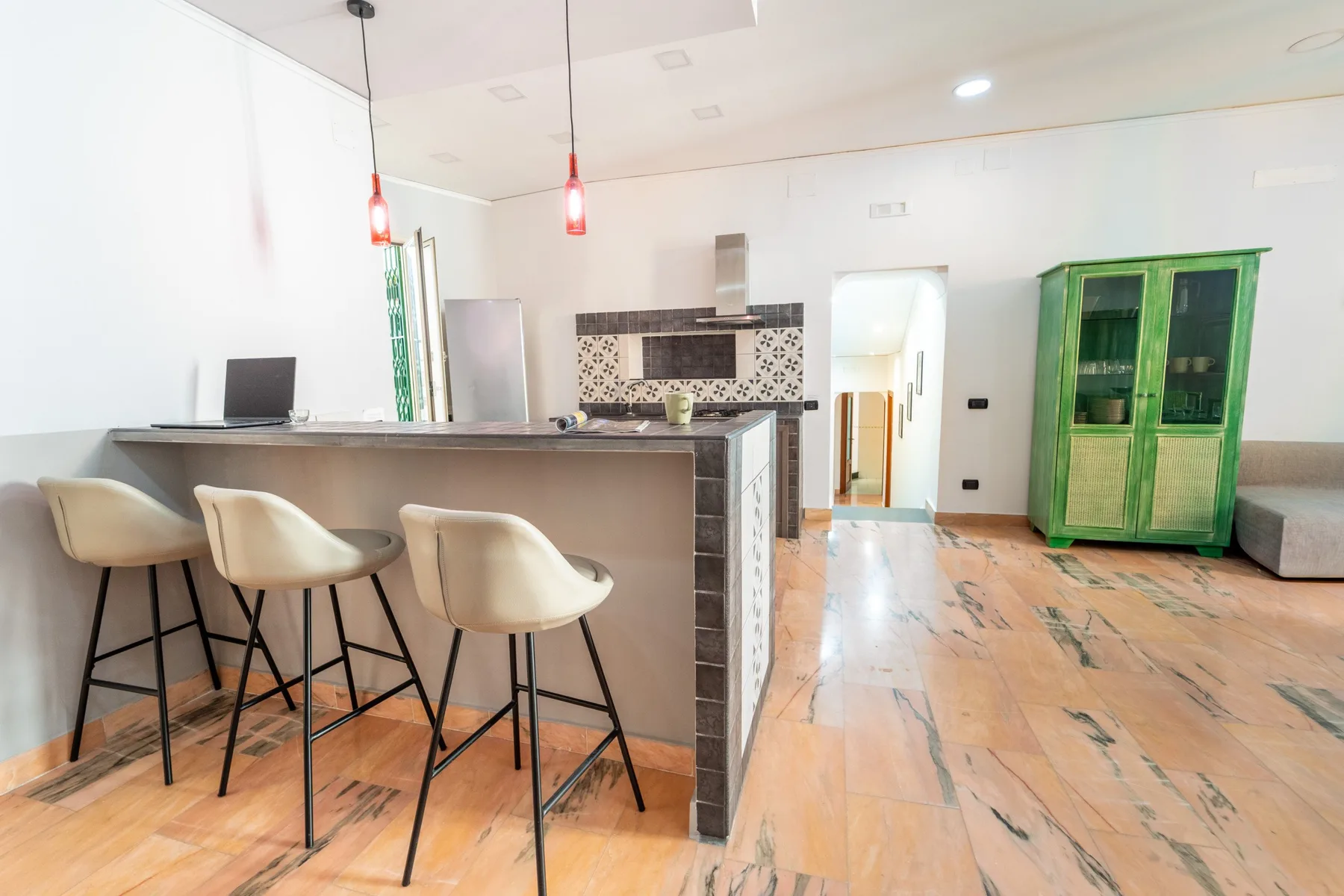 A modern kitchen with a counter, bar seating, and a green cabinet.