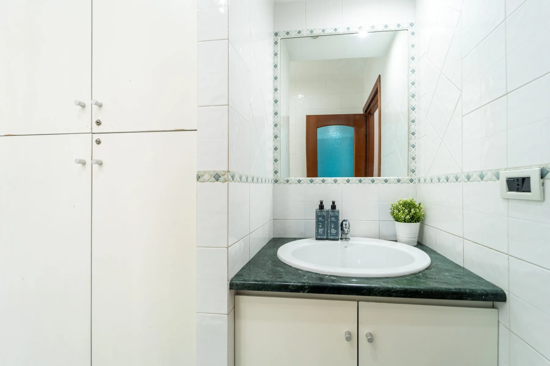 A bathroom vanity with a sink sits beneath a large wall mirror.