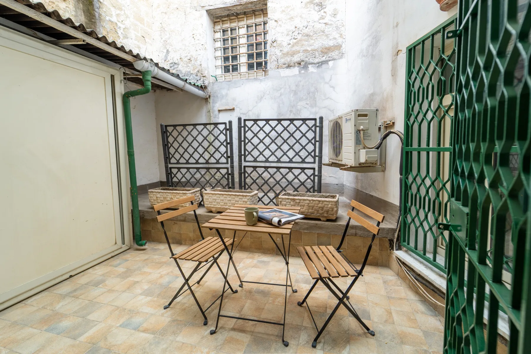 A small tiled patio with a folding table and outdoor seating.