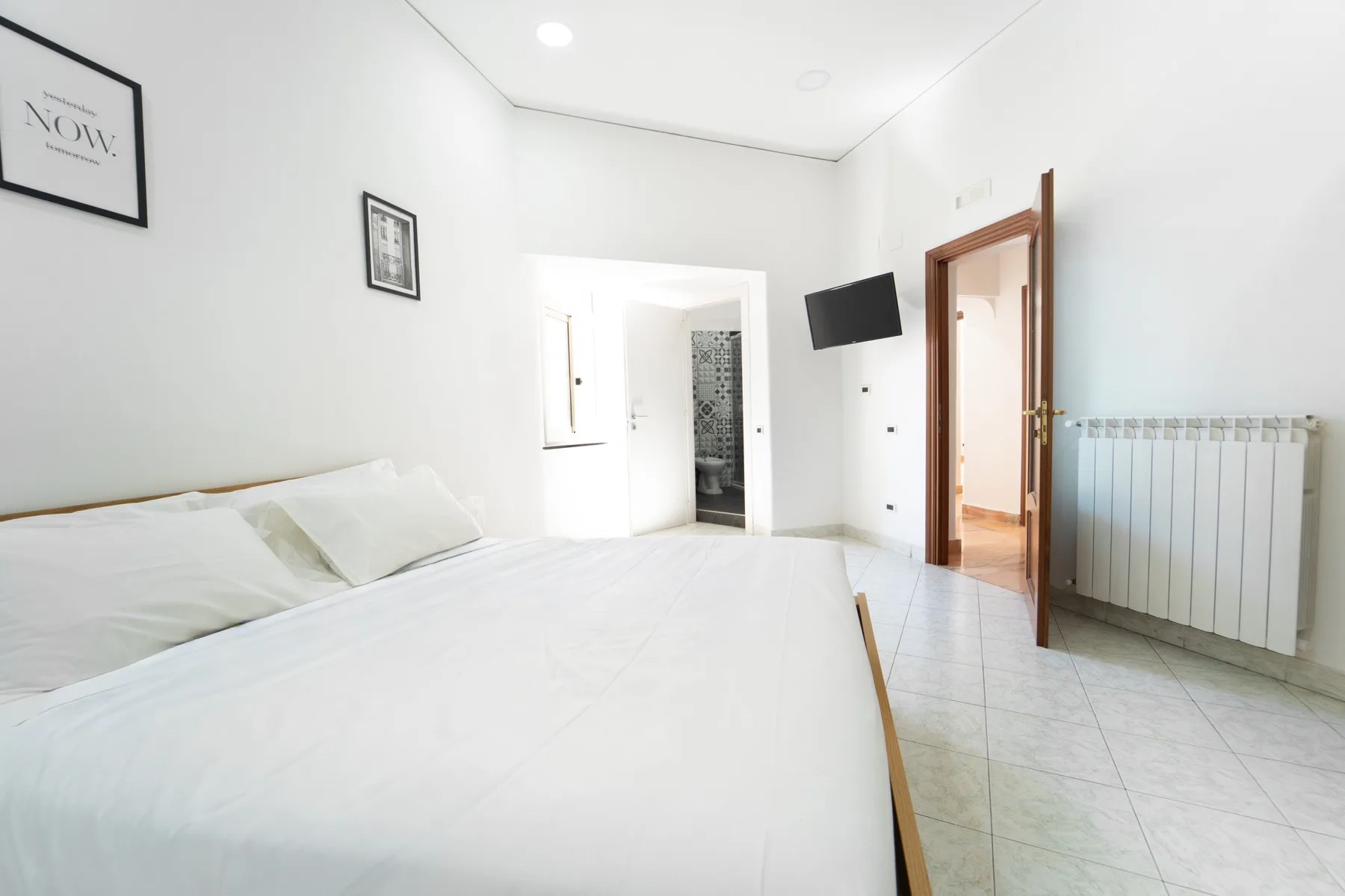 A bright bedroom with a large bed and an open doorway.
