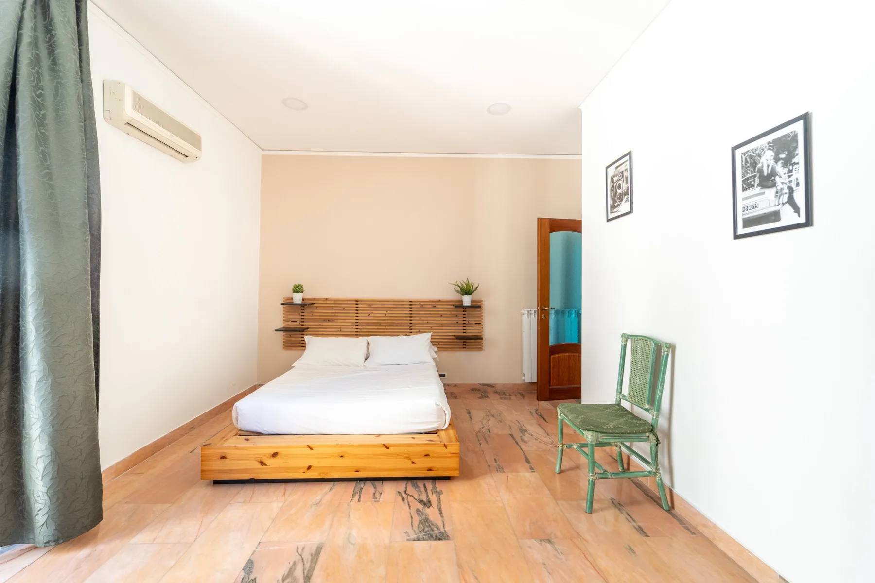 A bedroom with a low bed, a wooden headboard, and a chair.