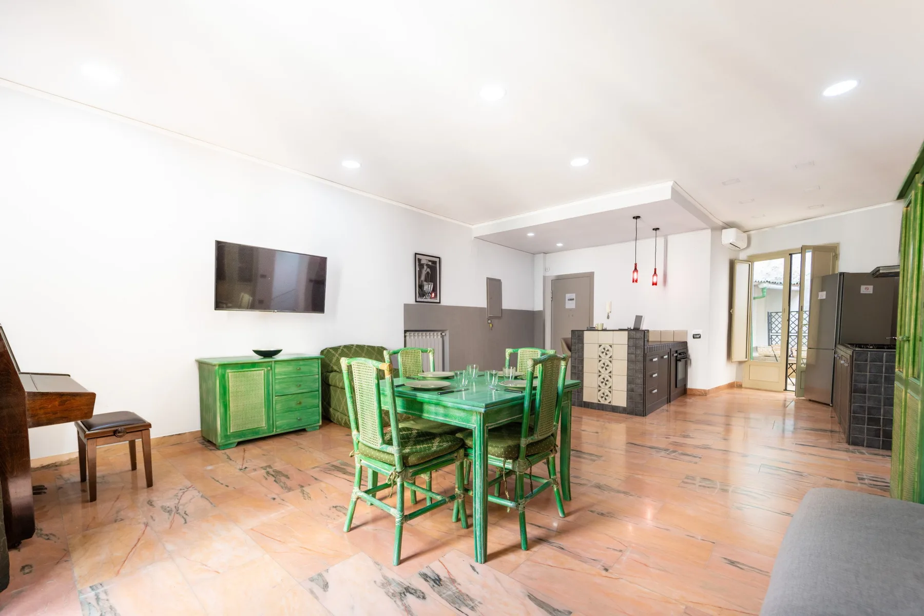 A dining area with a green table and chairs in a bright open room.