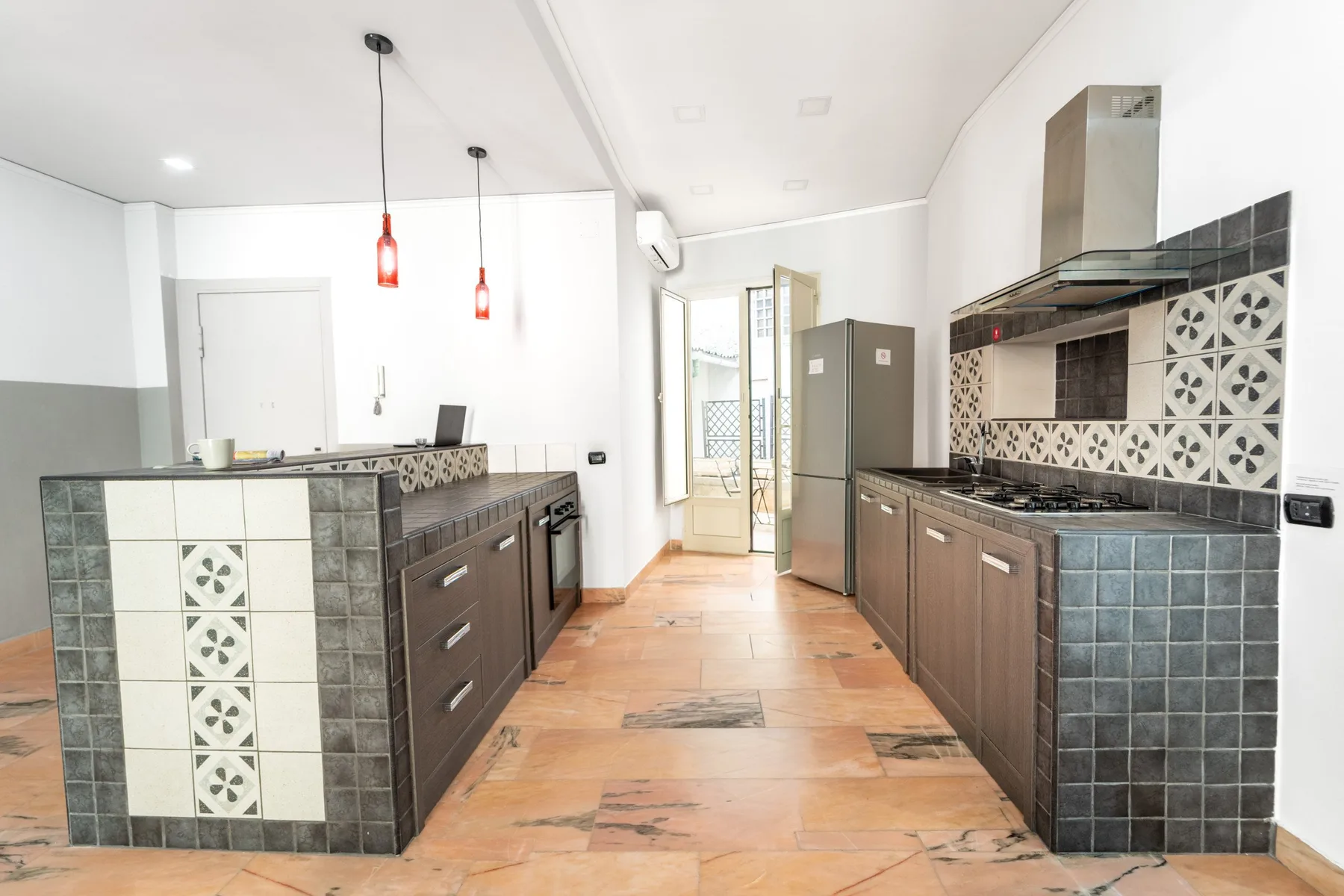 A galley kitchen with dark cabinets and a glass door at the far end.