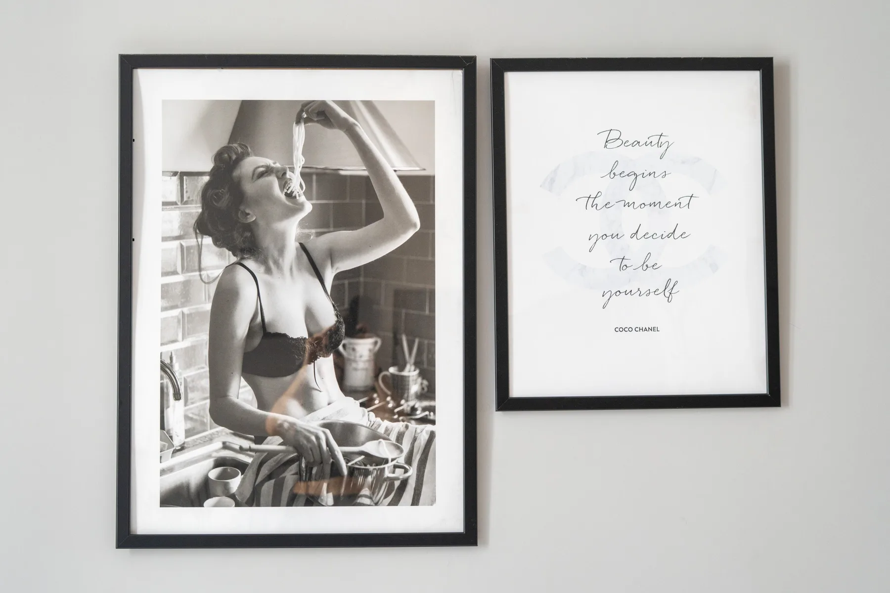 Two framed prints hang on a light wall, including a black-and-white kitchen photograph.