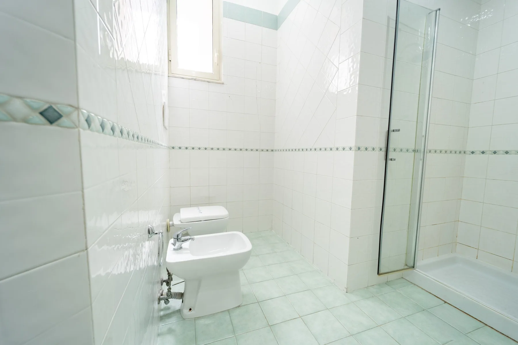 A tiled bathroom with a sink and a glass shower enclosure.