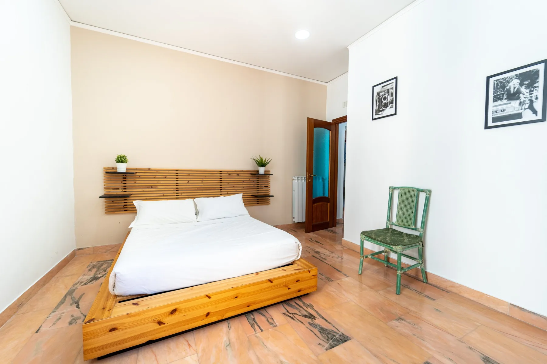 A bedroom with a white bed and a wooden headboard.