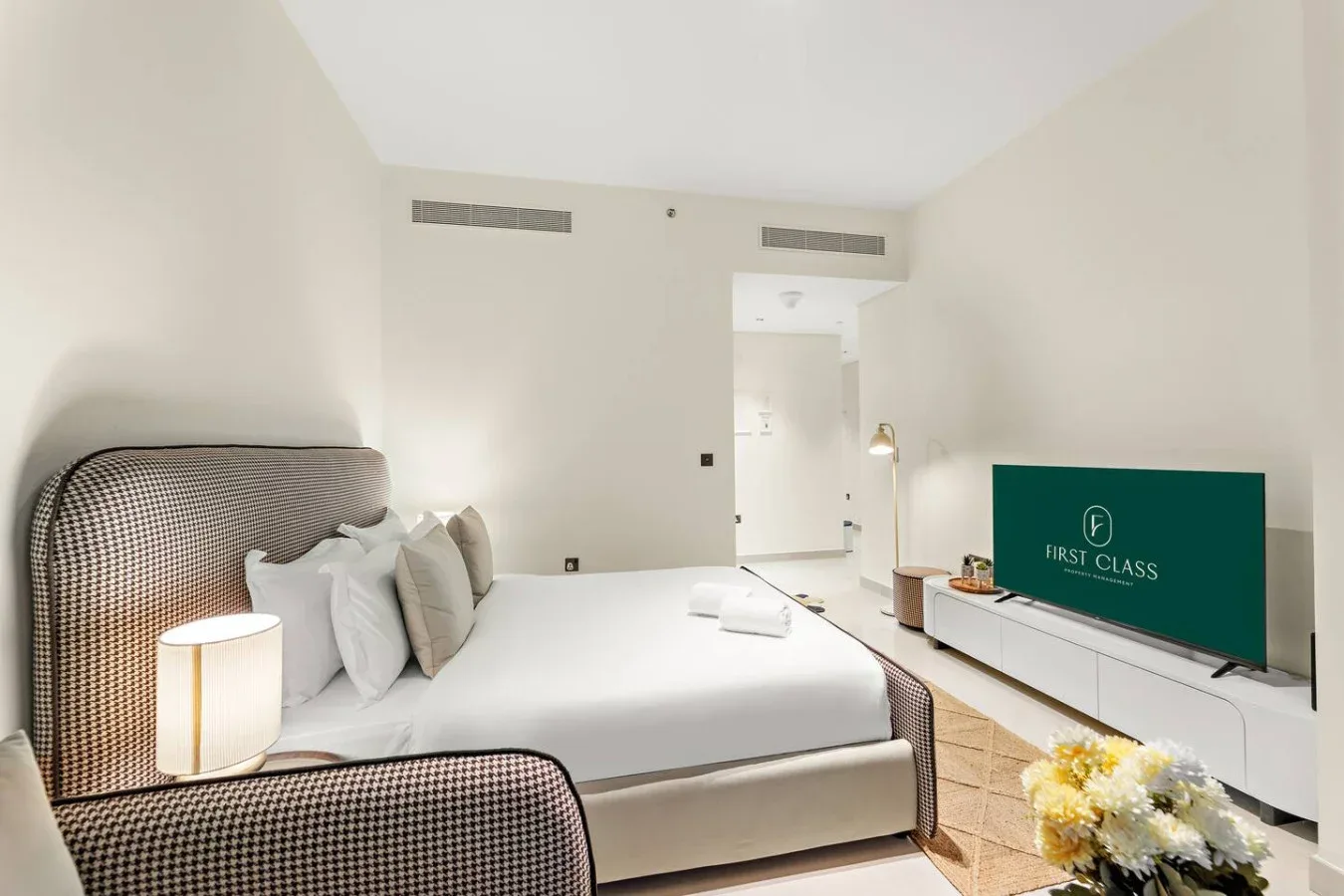 Un dormitorio con una cama grande, una lámpara de noche y un televisor.