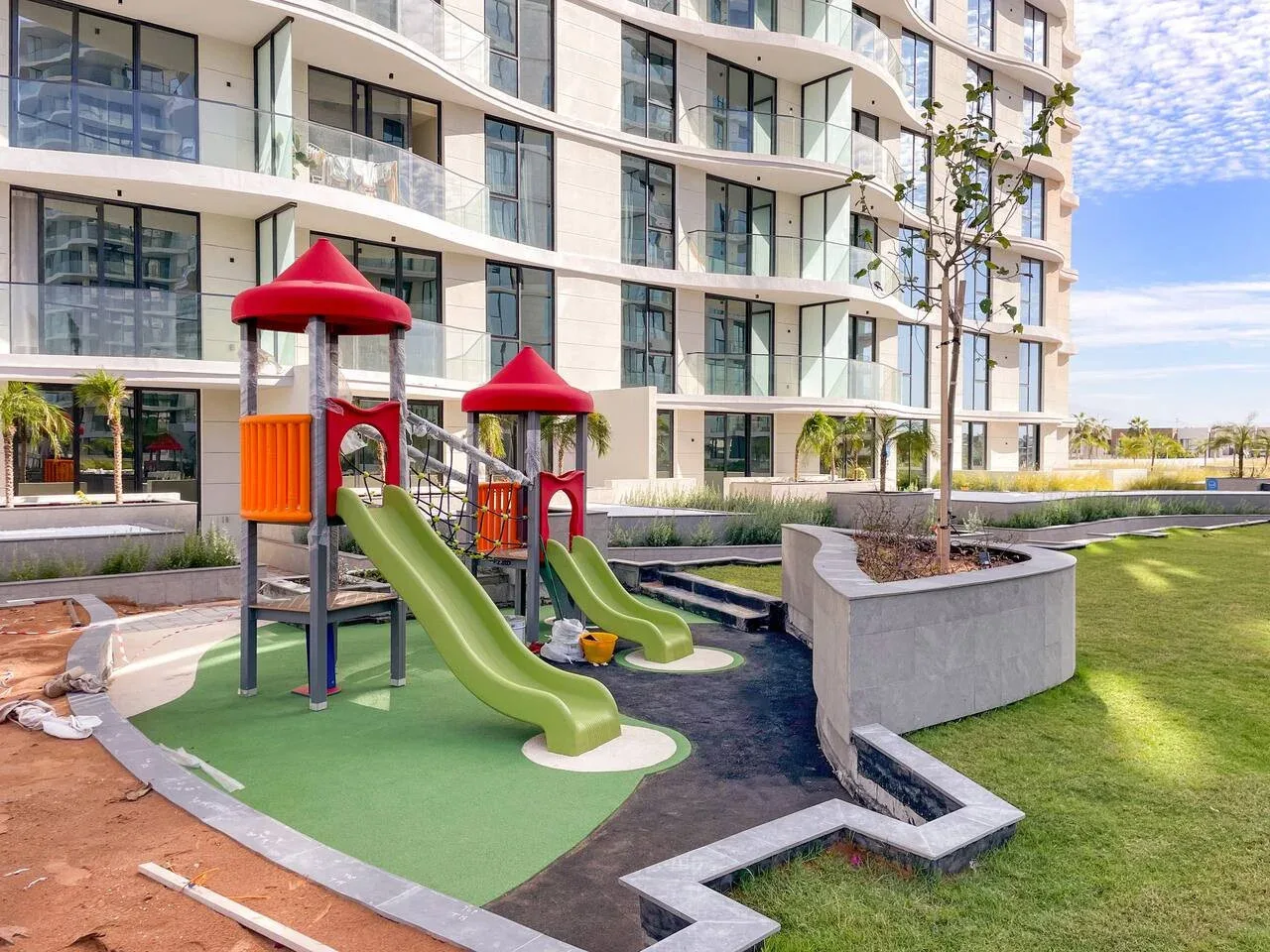 Un área de juegos al aire libre con toboganes de colores está junto a un edificio moderno.