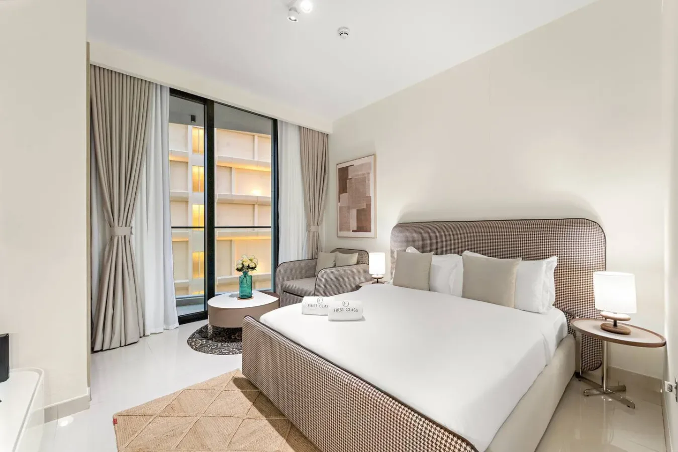 Un dormitorio luminoso con una cama tendida, mesitas de noche y una zona de estar.