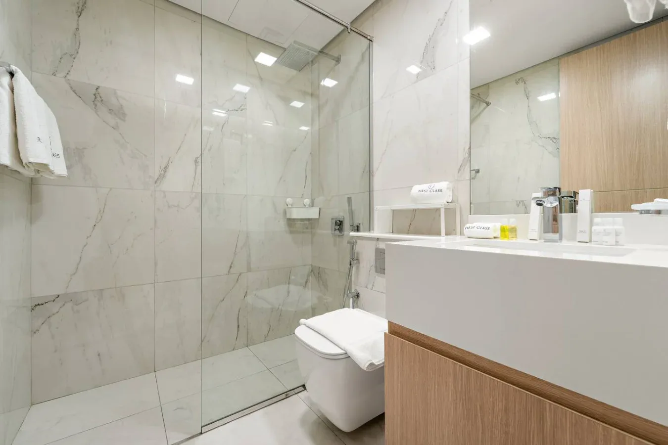 Un baño moderno con una ducha de vidrio y una encimera blanca con lavabo.