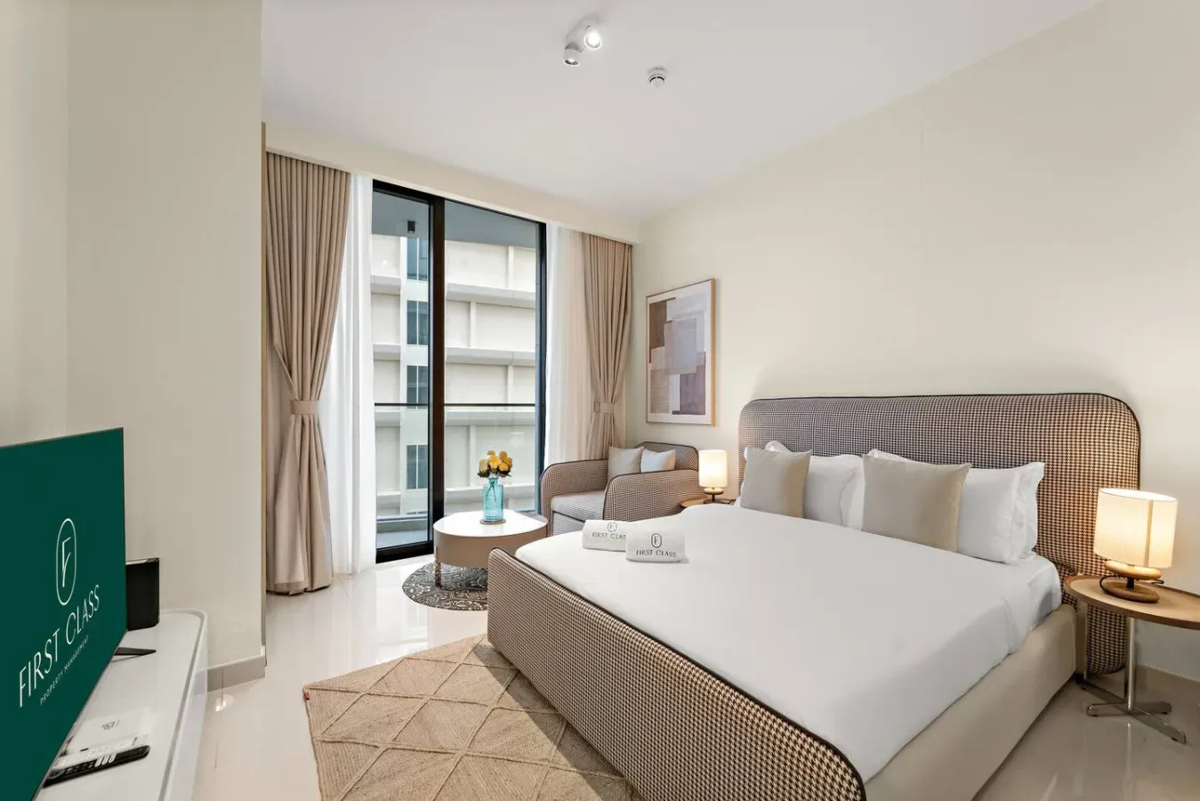 Un dormitorio luminoso con una cama grande junto a ventanas altas con cortinas.