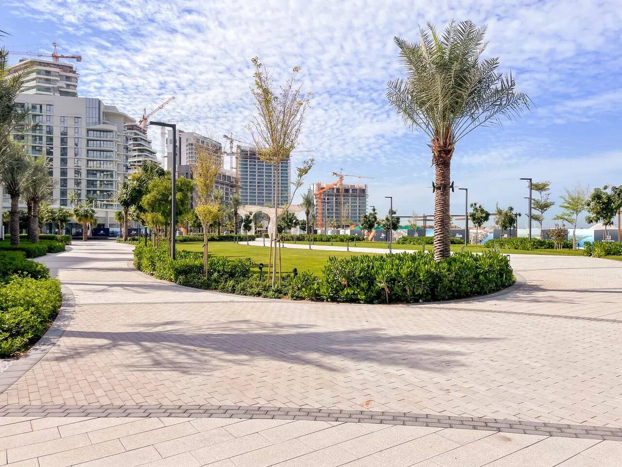Un paseo exterior ajardinado pasa junto a palmeras y edificios modernos.