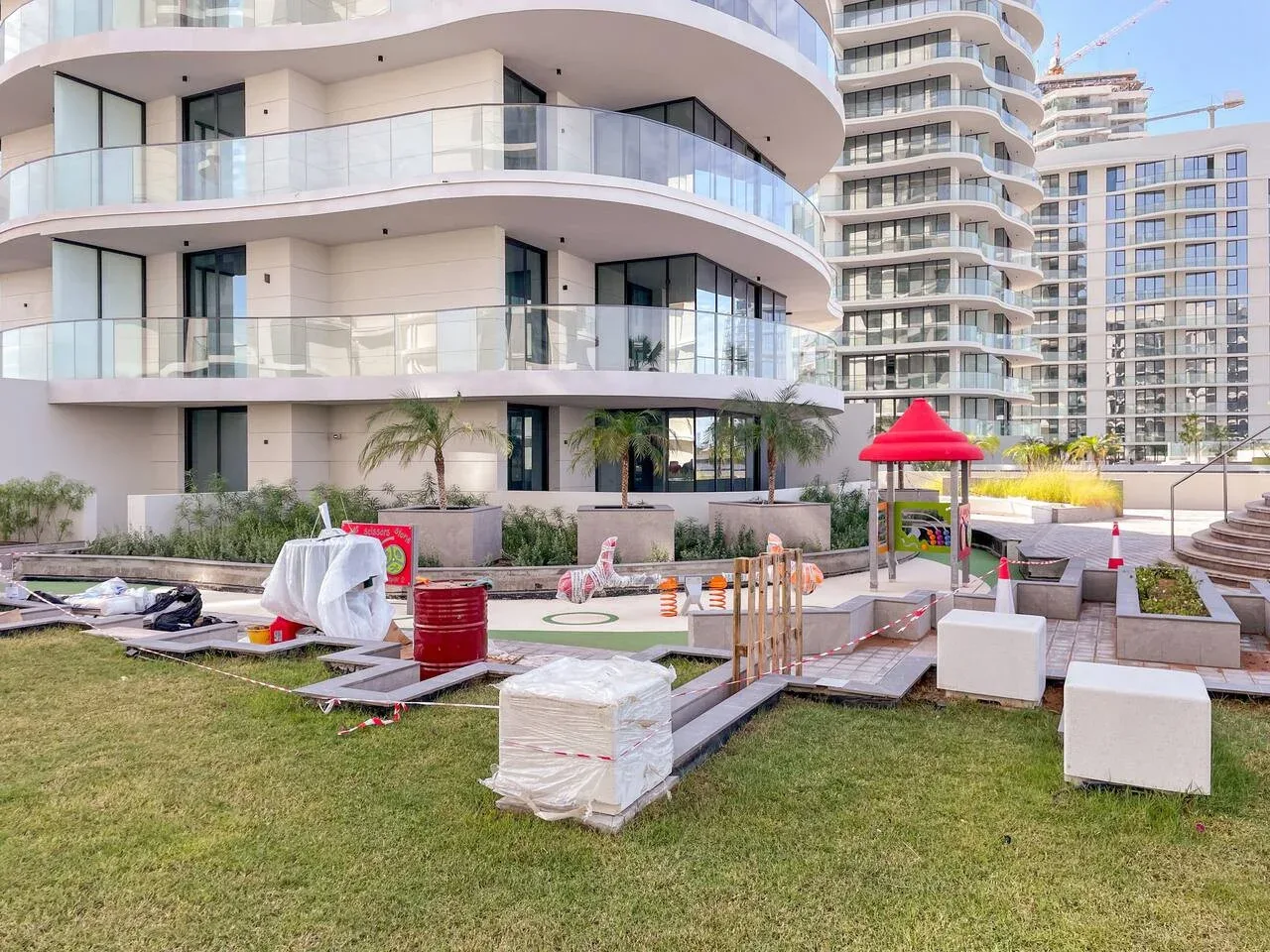 Zona ajardinada junto a edificios de apartamentos modernos, con una pequeña estructura de juegos.