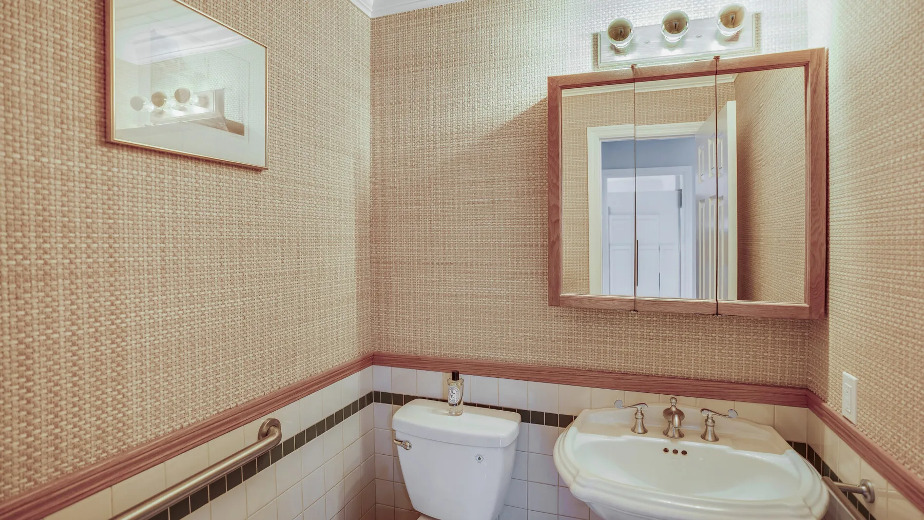 Un baño alicatado con un inodoro y un lavabo bajo un espejo.