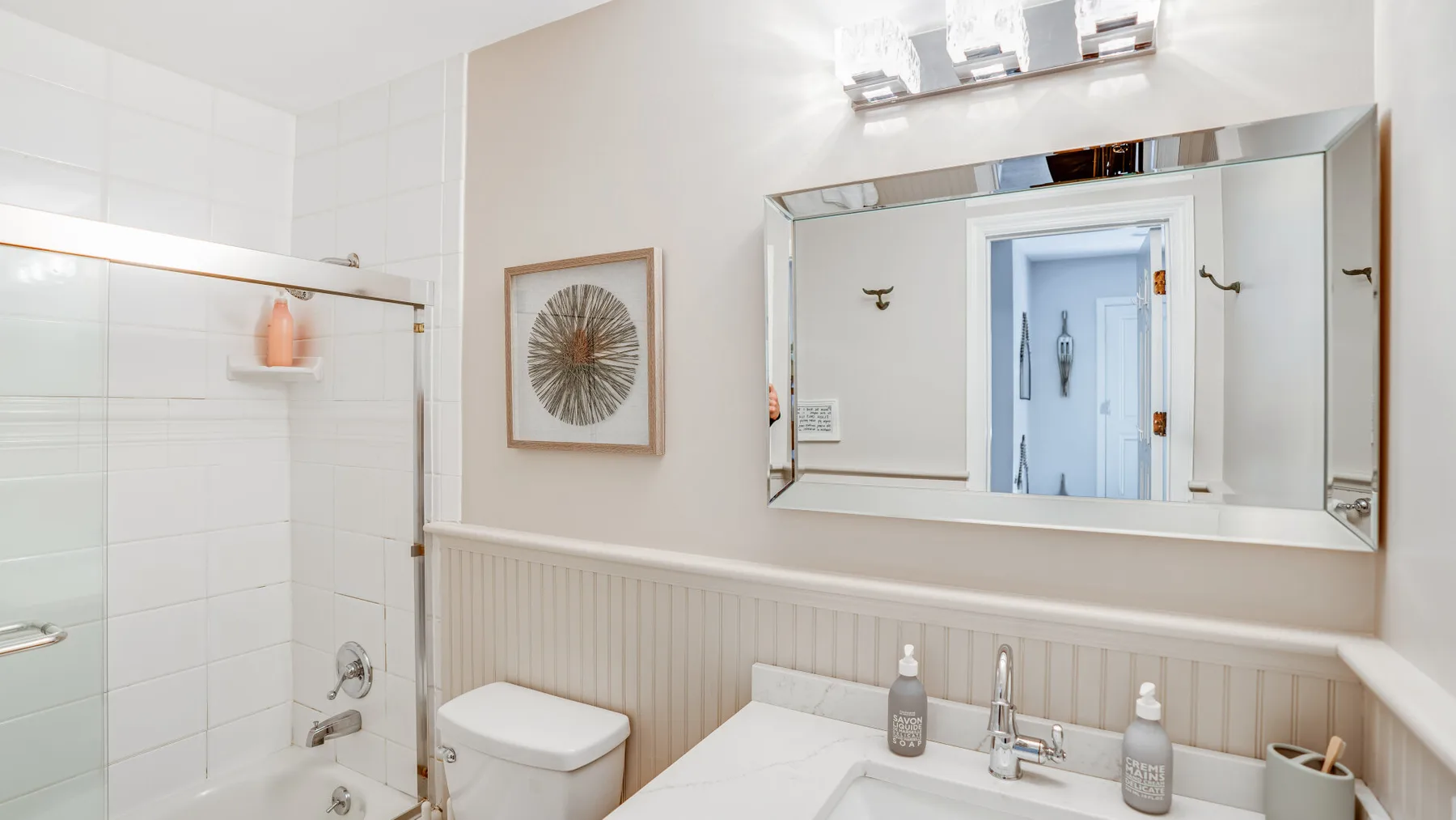 Un baño luminoso con bañera, lavabo y un gran espejo de pared.