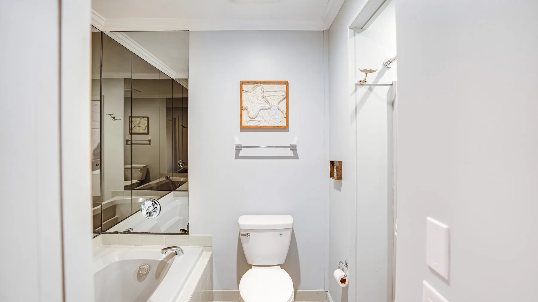 Un baño luminoso con bañera, mampara de ducha de vidrio e inodoro.
