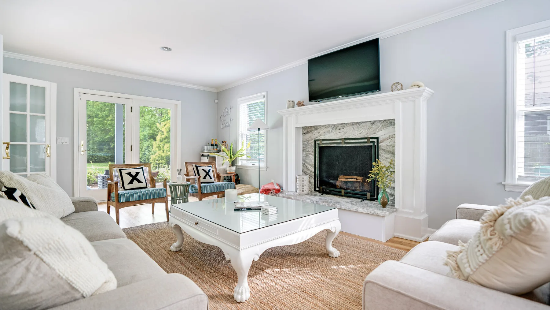 A bright living room with seating arranged around a white coffee table and fireplace.