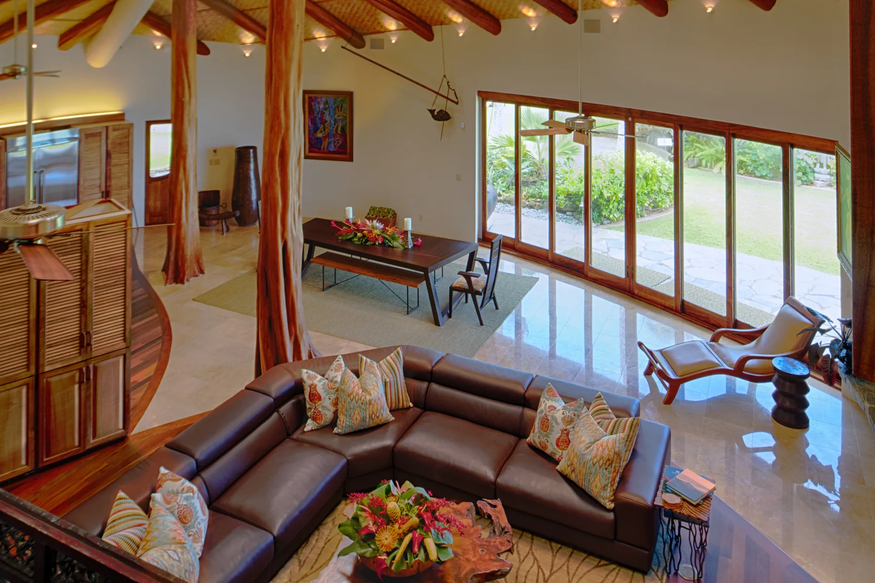 Una amplia sala de estar tiene asientos de cuero y grandes ventanales con vistas a la vegetación.