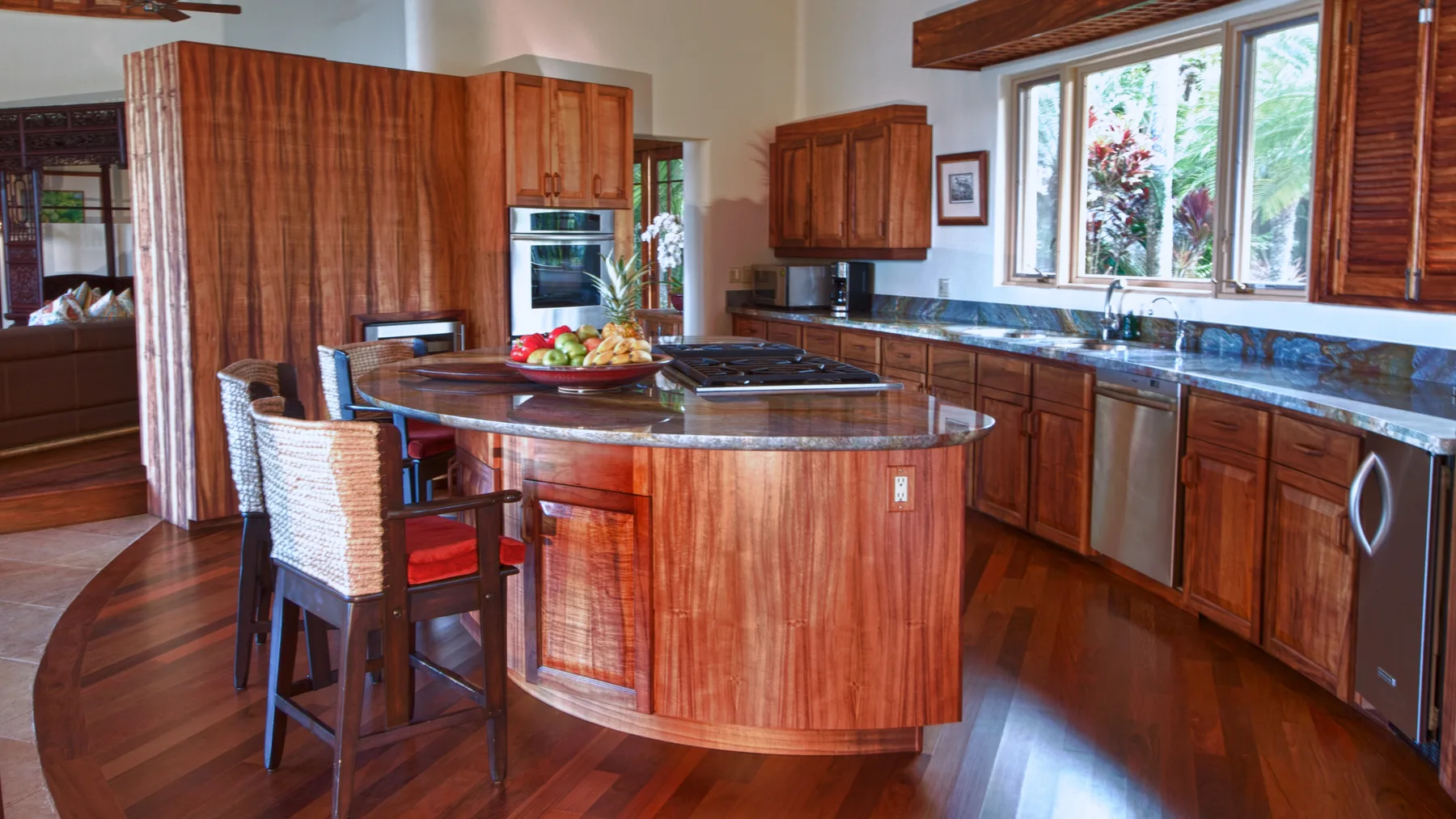 Una cocina con paneles de madera, una isla central y asientos en la barra.