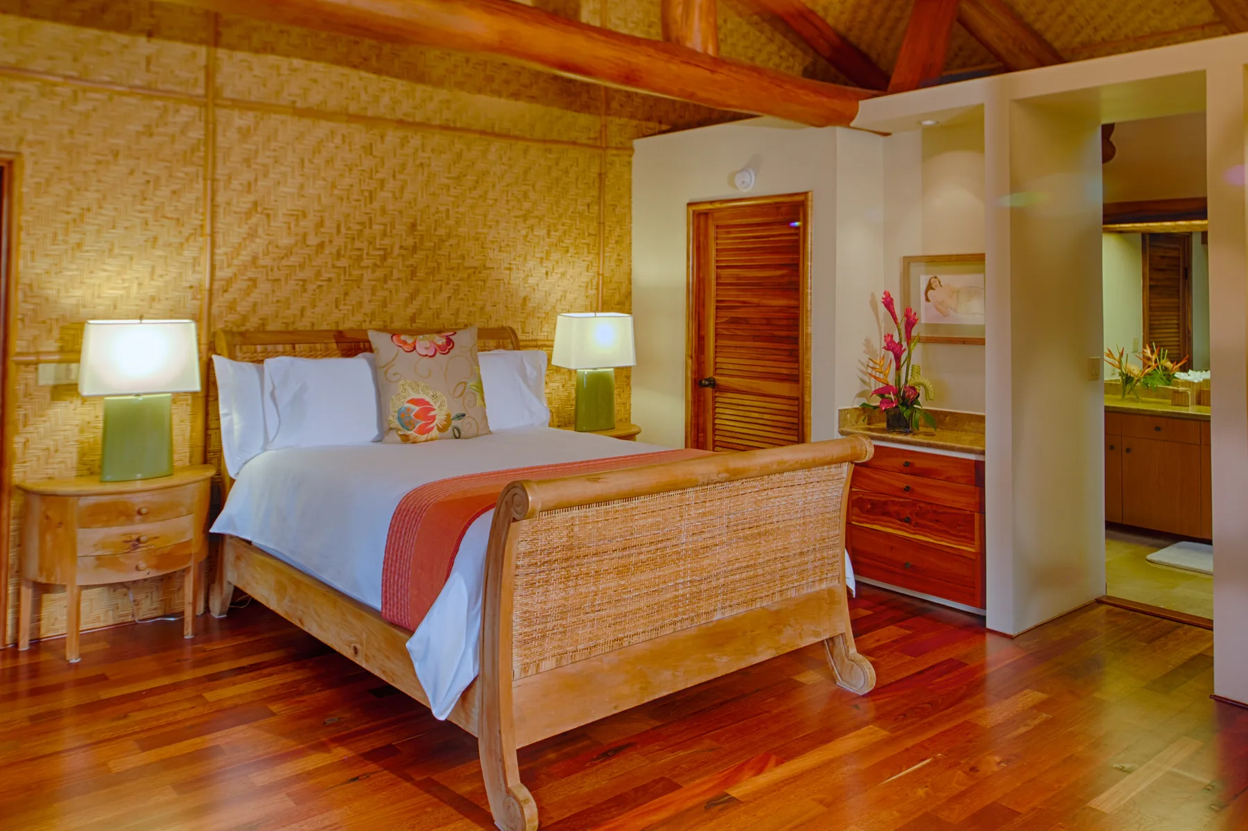 Un dormitorio con una cama, muebles de tejido y cálidos pisos de madera.