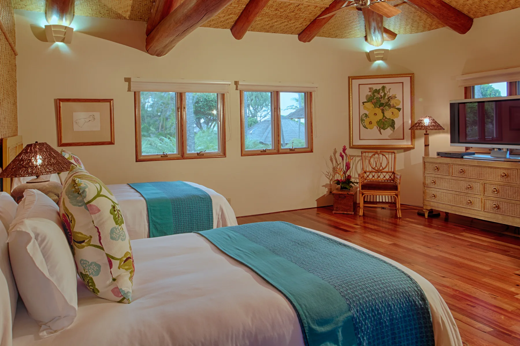 Un dormitorio con camas, ventanas y una cómoda bajo un techo con vigas de madera.