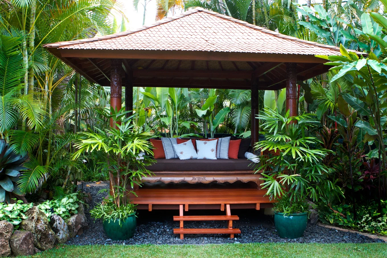 Una zona de estar cubierta al aire libre está rodeada de plantas tropicales.