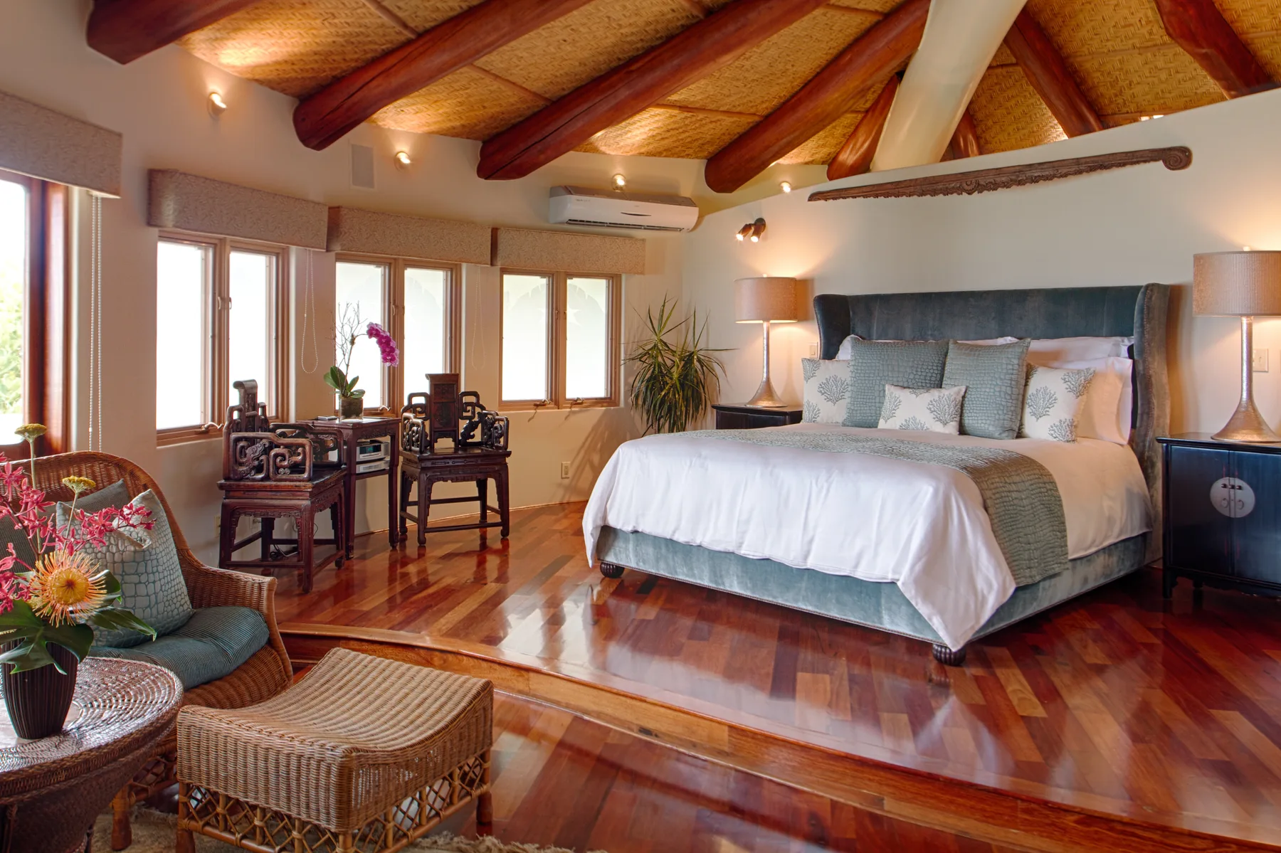 Un dormitorio con una cama grande, un escritorio y vigas de madera a la vista.