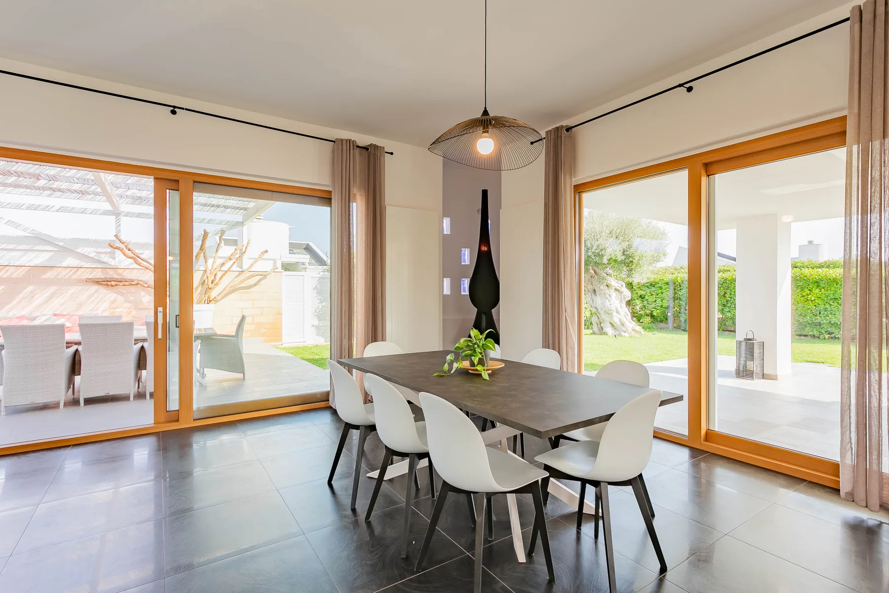 Comedor con mesa y sillas junto a grandes puertas de cristal.
