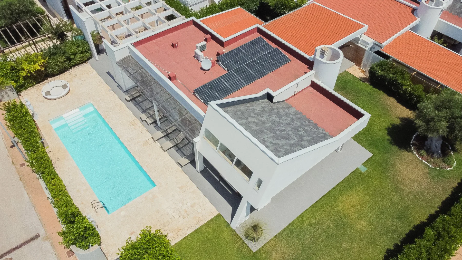 Vista aérea de un edificio moderno junto a una piscina y un césped.
