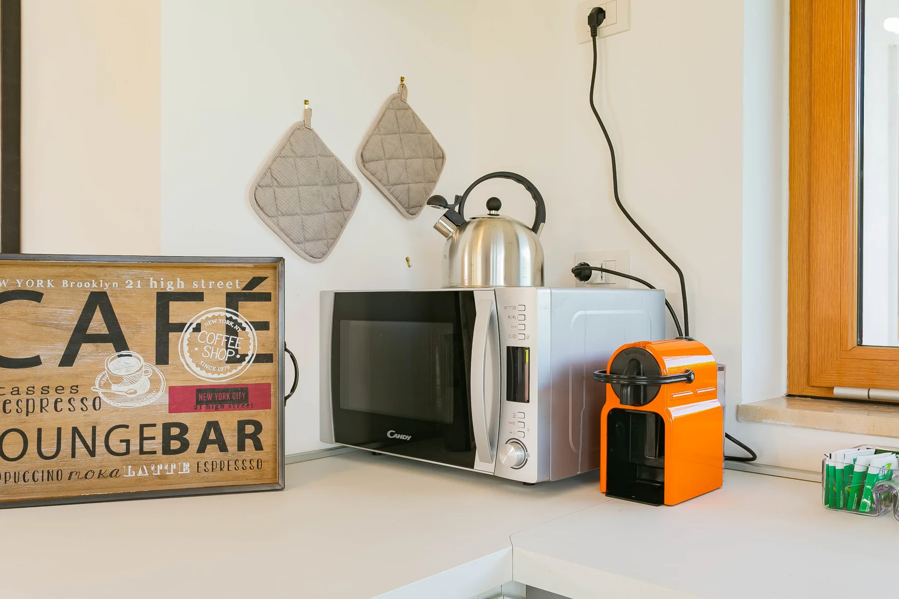 Una encimera de cocina con hervidor, microondas y cafetera naranja.
