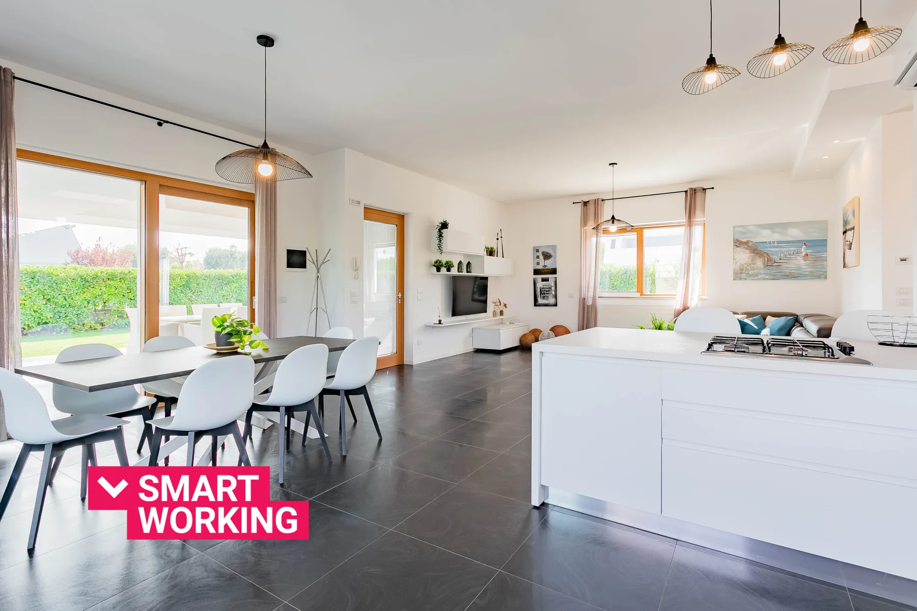 Una luminosa sala de estar y comedor diáfana con grandes ventanas y muebles modernos.