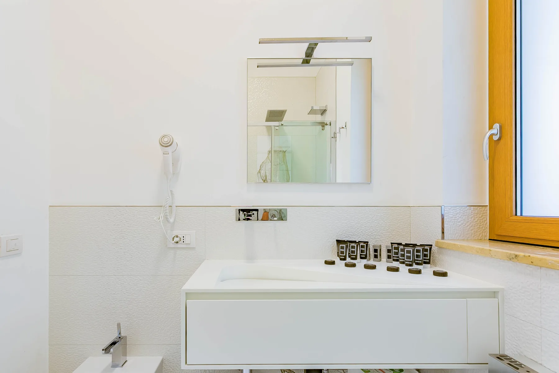 Un baño luminoso con un espejo de pared sobre un lavabo.