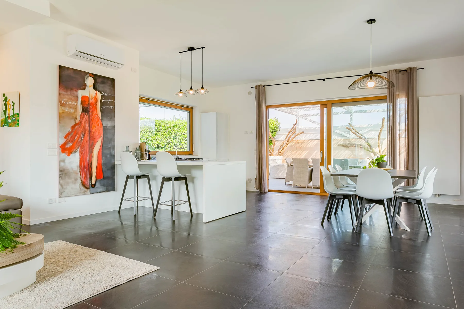 Una luminosa cocina y comedor de planta abierta, con grandes ventanas y una mesa de comedor.
