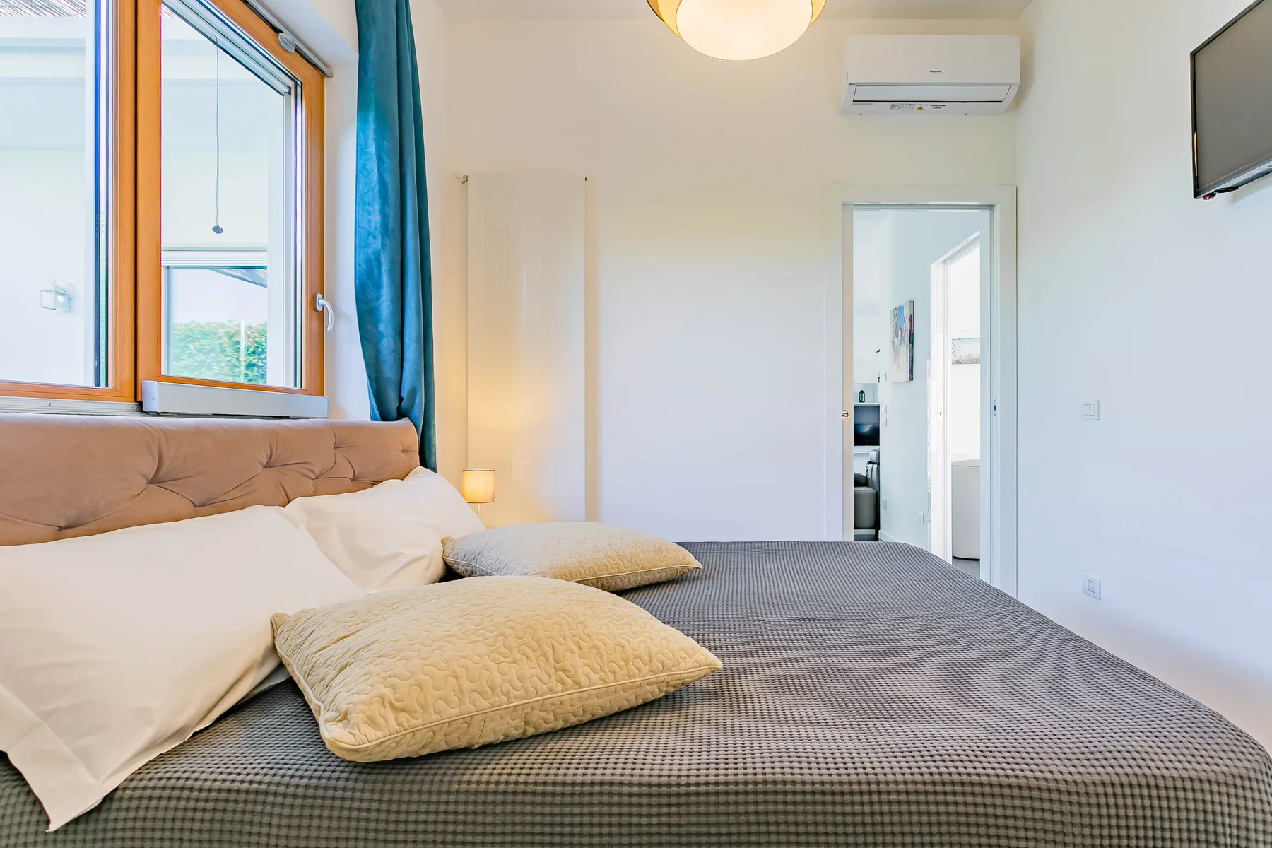 Un dormitorio con una cama bajo una ventana y una puerta abierta.