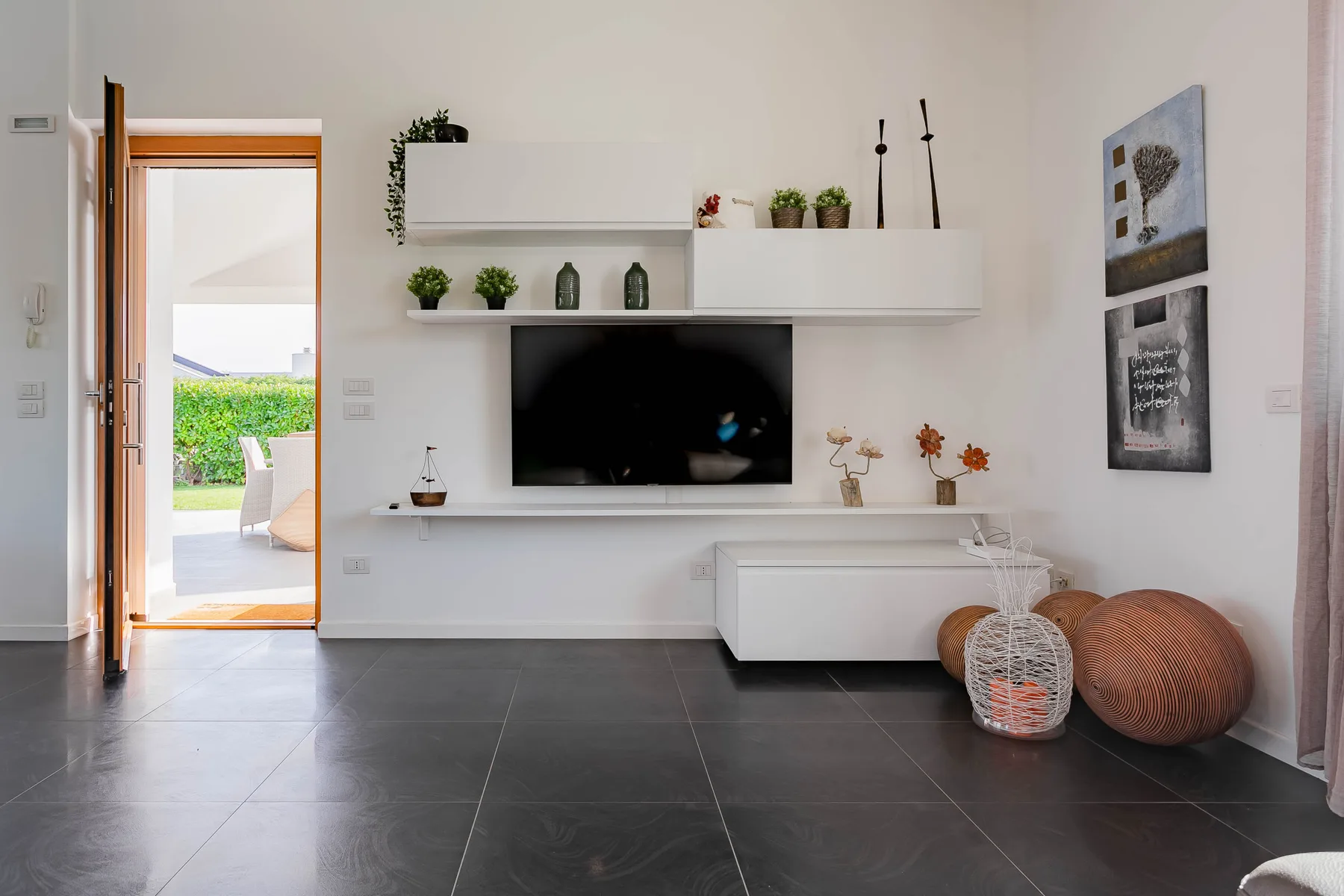 Una sala luminosa con un televisor debajo de una repisa flotante.