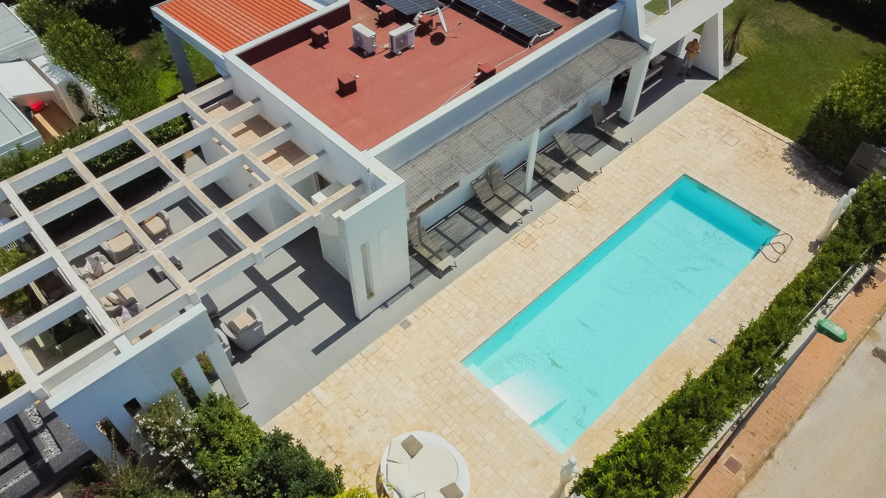 Una vista aérea muestra una piscina rectangular junto a un edificio moderno.