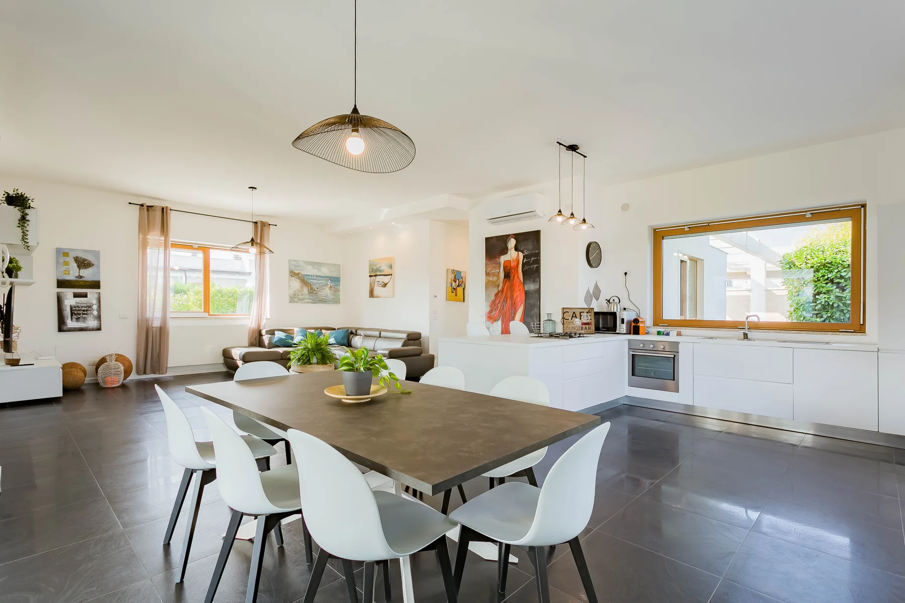 Una cocina y comedor de planta abierta con una mesa grande y asientos blancos.