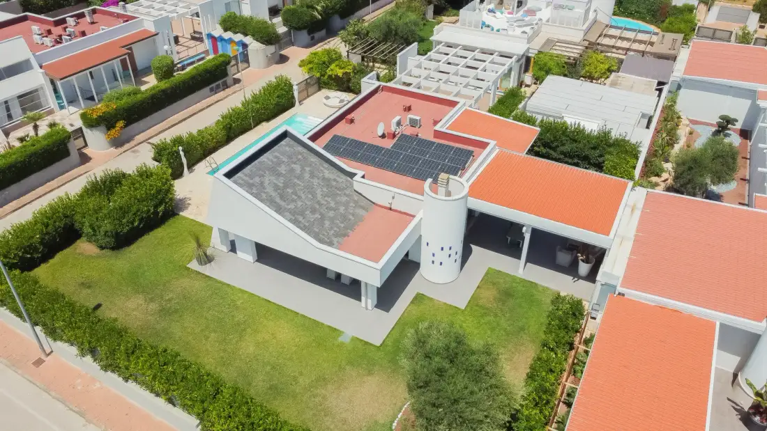Vista aérea de edificios modernos con techos rojos, paneles solares y jardines.