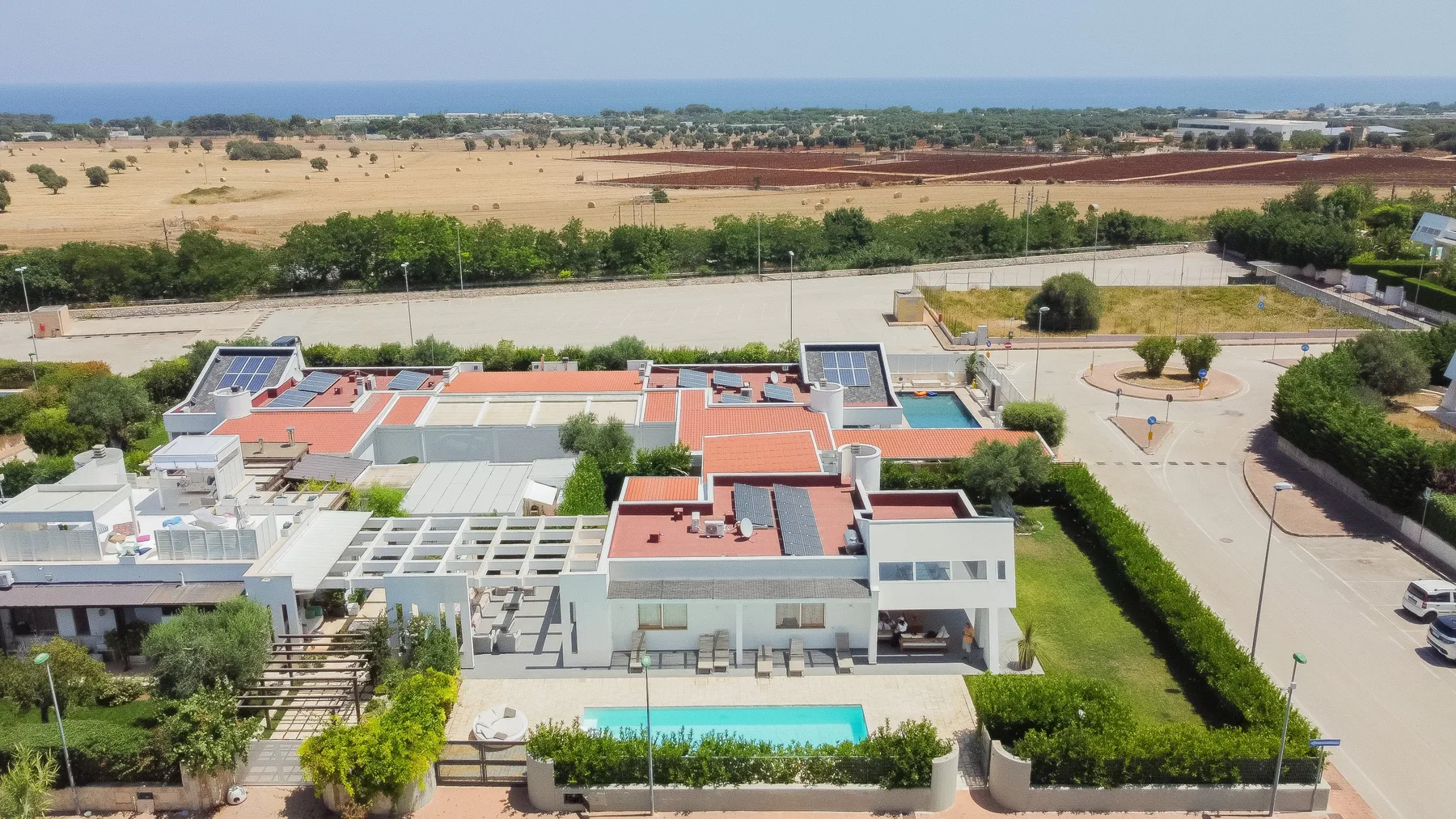 Vista aérea de un edificio moderno con una piscina turquesa y jardines.