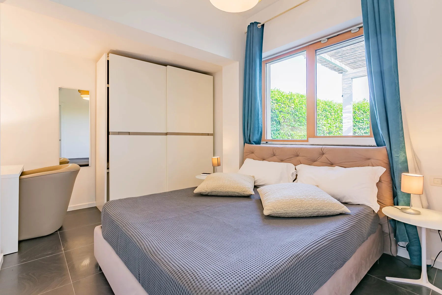 Un dormitorio con una cama bajo una ventana enmarcada por cortinas azules.