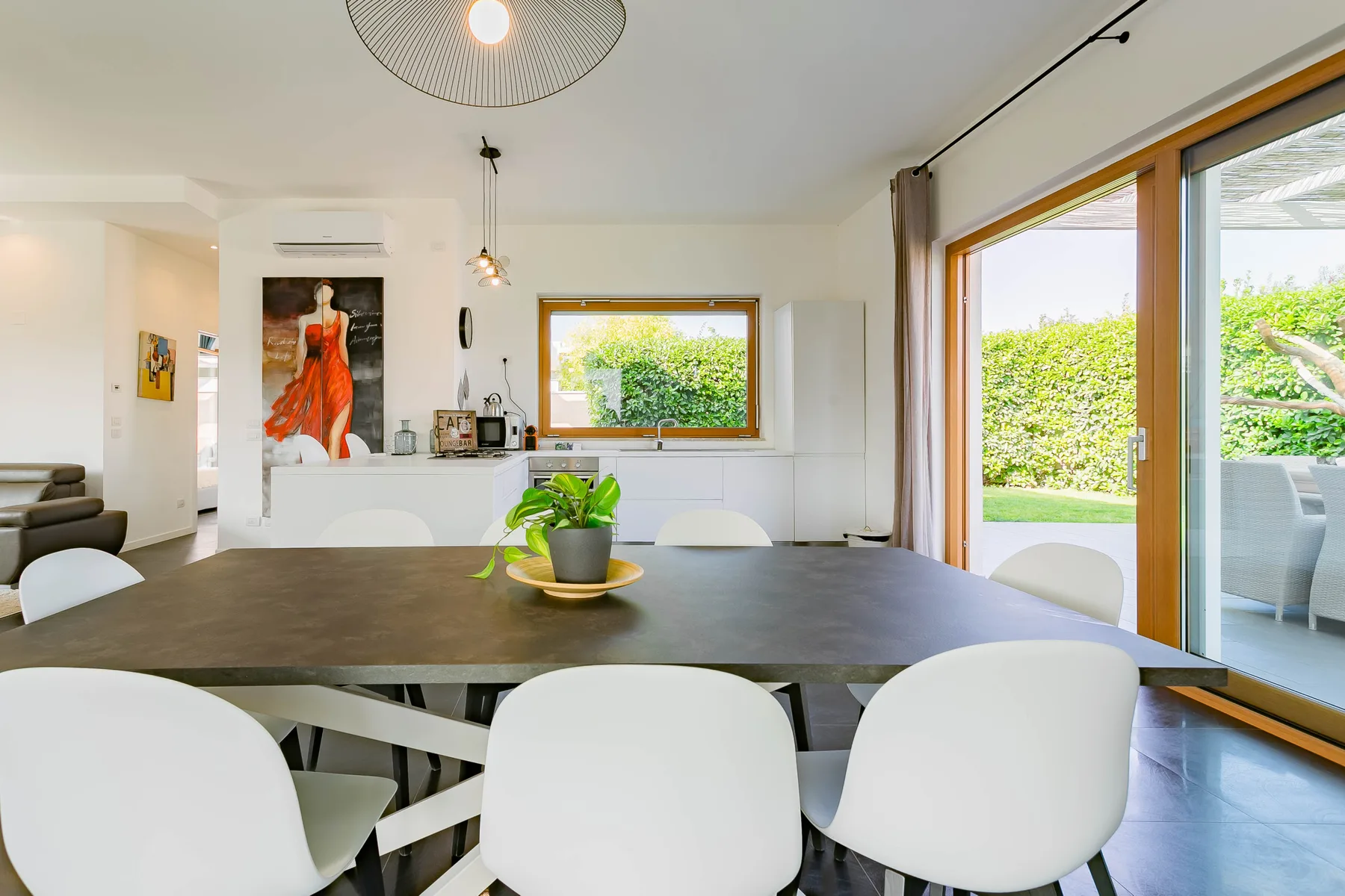 Un comedor luminoso con una mesa larga y grandes ventanas con vistas a la vegetación.
