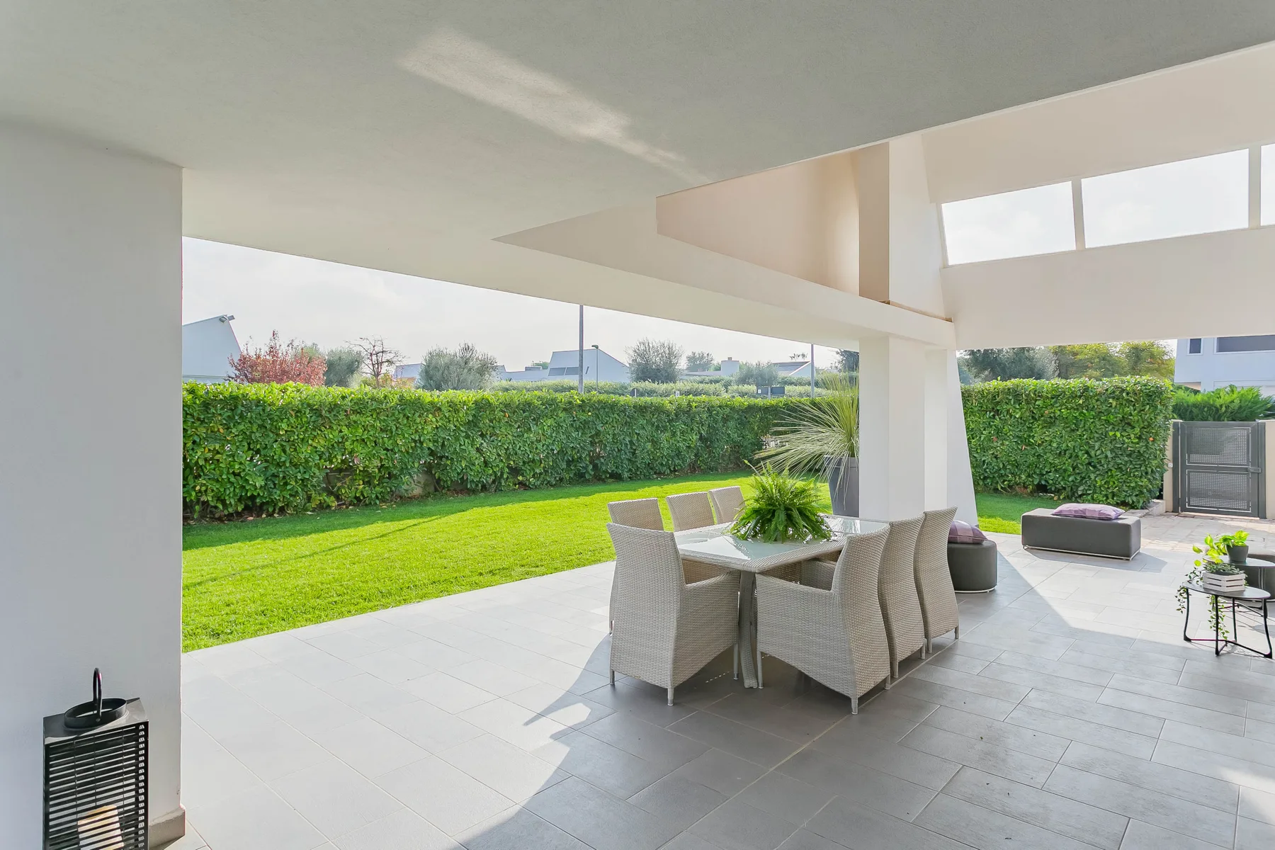 Un patio cubierto con asientos al aire libre y vistas al jardín.