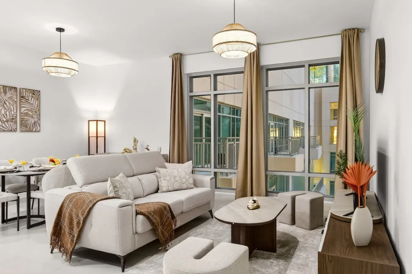 Una sala luminosa con asientos, una mesa de centro y ventanas grandes.