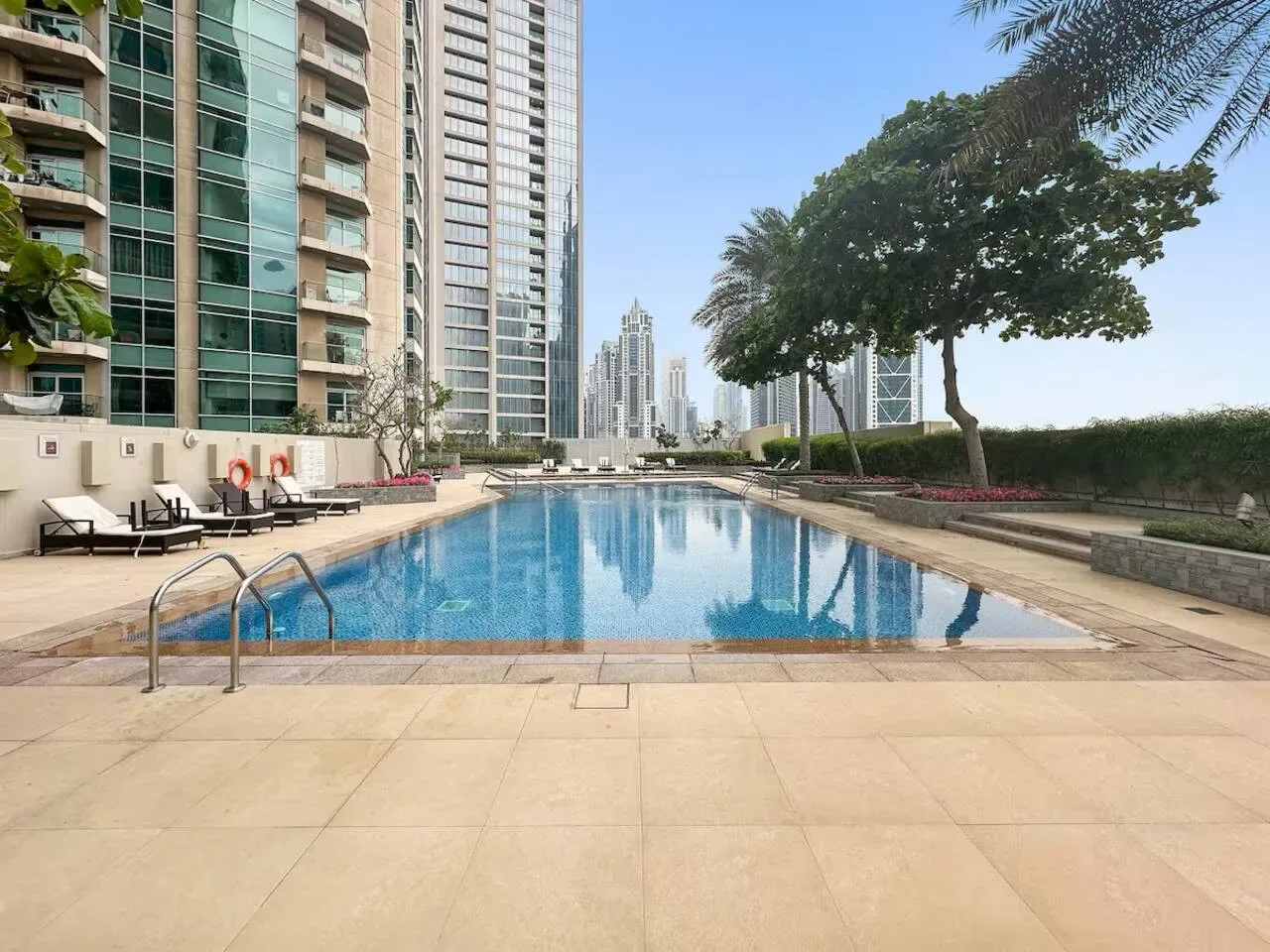 Una piscina al aire libre junto a edificios altos, con asientos junto al borde.