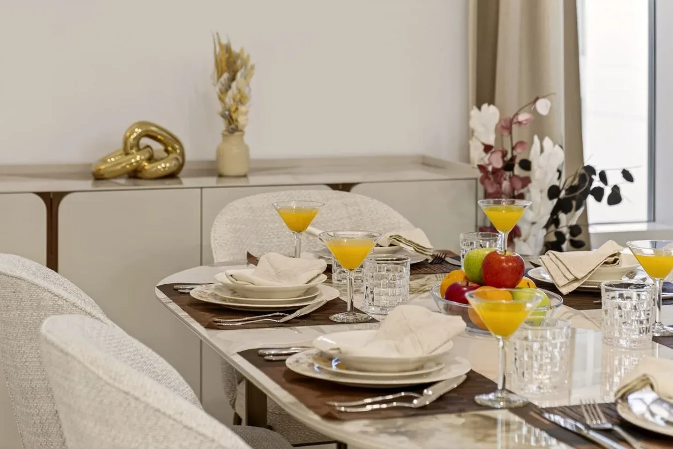 Una mesa de comedor está preparada con platos, vasos y bebidas de colores.