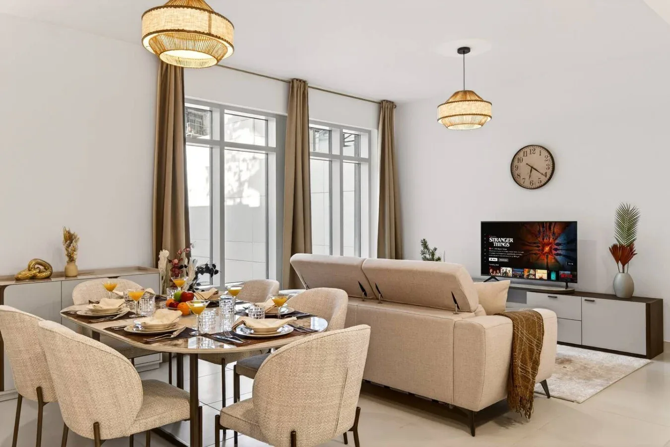 Una luminosa sala de estar y comedor con asientos, mesa de comedor y grandes ventanas.