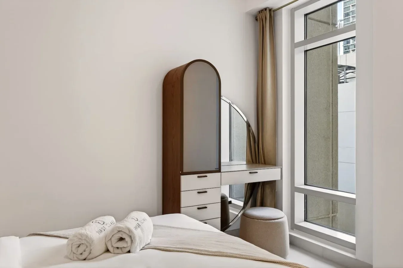 Un dormitorio con una cama junto a un tocador y una ventana grande.