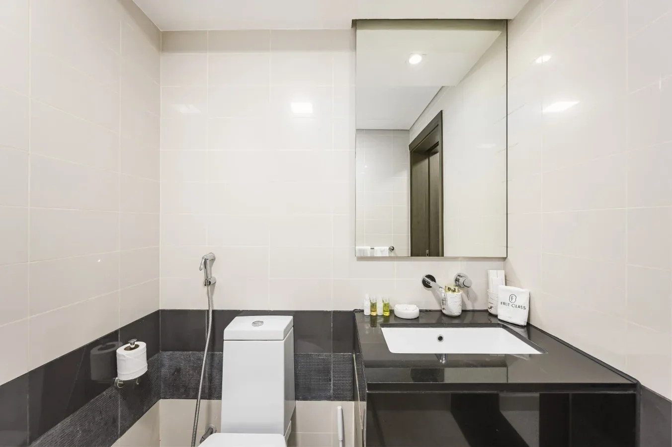 Un baño revestido de azulejos con inodoro, lavabo y un gran espejo.