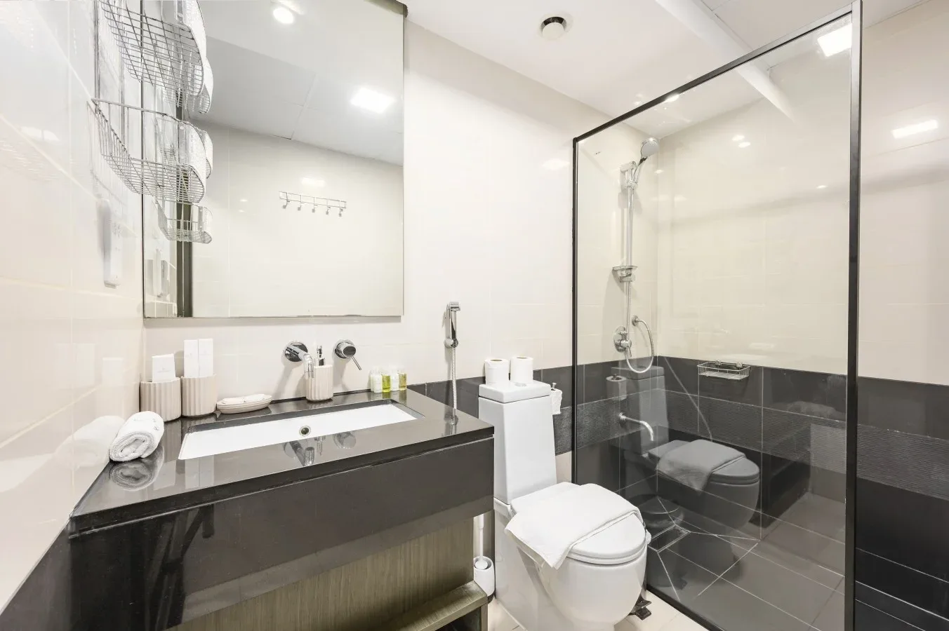 Un baño con lavabo, inodoro y ducha con mampara de vidrio.