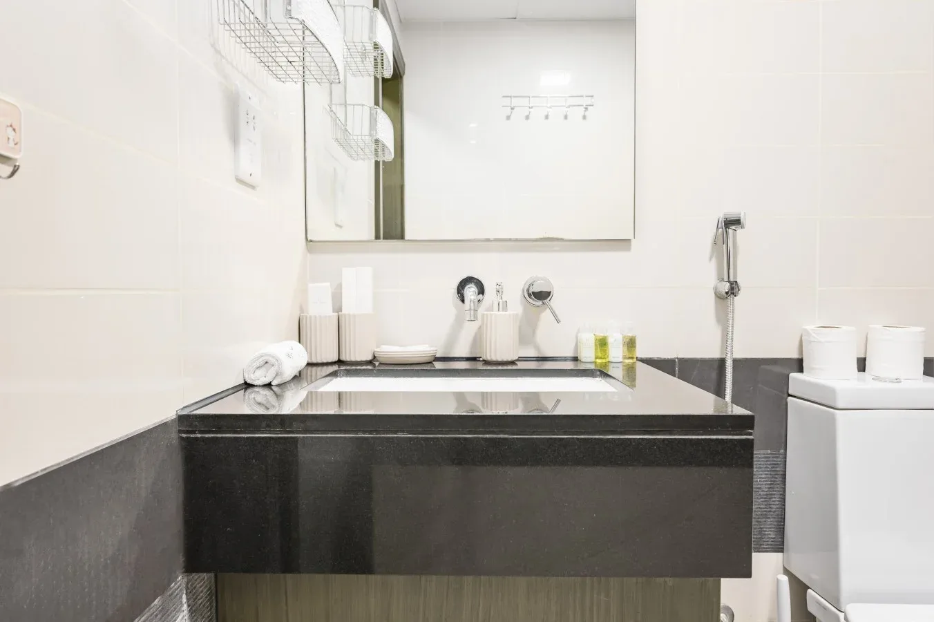 Un tocador de baño con un espejo amplio y artículos de aseo sobre la encimera.
